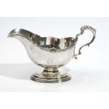 A silver large sauceboat, with a scrolling handle, shaped rim and raised on an oval foot,