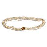 A three row necklace of cultured pearls, on a gold and citrine set seven stone cluster clasp,