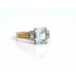 An 18ct two colour gold ring, claw set with a cut cornered rectangular step cut aquamarine,