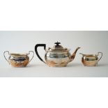 A silver three piece tea set, comprising; a teapot with black fittings,