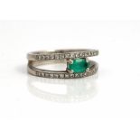 An 18ct white gold, emerald and diamond ring, claw set with an oval cut emerald at the centre,