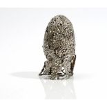 A silver model of a hinged egg enclosing a tiger,