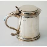 A silver hinge lidded tankard of tapered cylindrical form with a cast scrolling thumb piece to the