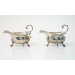 A George III pair of silver sauceboats, each having a shaped rim,