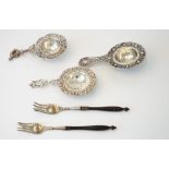 A Dutch tea strainer, decorated with a floral border, the handle finial modelled as a milkmaid,