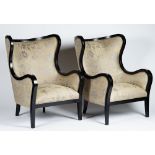 A pair of contemporary wing armchairs with ebonised frames,