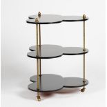 An ebonised and gilt metal clover-leaf shape three tier table, 56cm wide x 69cm high.