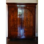 A Biedermeir mahogany armoire, the moulded cornice above a pair of arched panel doors,