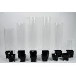 Two sets of six square tapering black glass vases, in two graduated sizes,