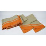 A set of three green linen tablecloths, bordered in orange.