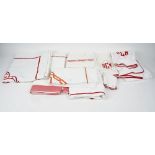 A set of matching towels, flannels and bed linen, white with red trim and initials 'DCM',