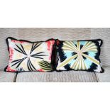 Two cushions, with large multicoloured wild flower pattern, with ruched black chintz trim.