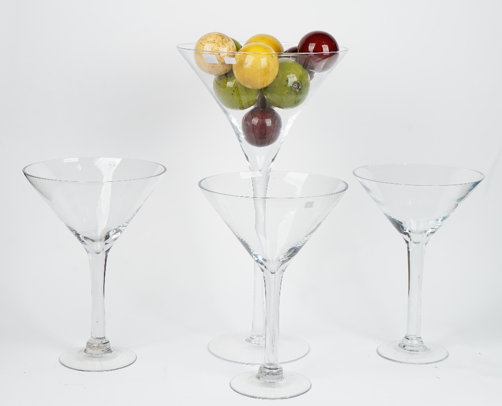 A tall contemporary glass goblet containing a collection of faux marble balls and three smaller