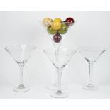 A tall contemporary glass goblet containing a collection of faux marble balls and three smaller