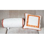 A scrunched cream silk bolster cushion, with braided ends,