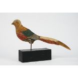 A polychrome painted wooden figure of a pheasant on an ebonised block wooden base.