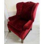 A 20th century red upholstered winged ar