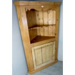 A large late Victorian pine freestanding corner display cupboard with open shelves above a large