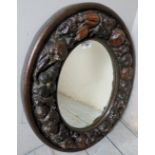 An antique oval wall mirror with papier mache fruit,