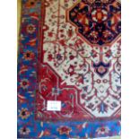 A late 19's/20's Persian rug with central motif on cream ground, bordered in blue. 177cm x 133cm.