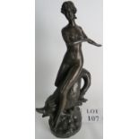 A patinated bronze statue of a female figure being carried on a dolphin's back,