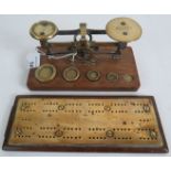A set of small postal scales with weights and a brass cribbage board.