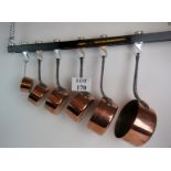 A set of 5 French graduated copper saucepans with iron handles, and one other similar,