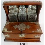 A Victorian oak tantalus with silver plated mounts, three cut glass decanters, key,