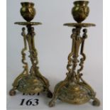 A pair of brass candlesticks of elaborate design with classical motifs, 24cm tall.