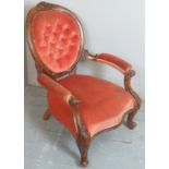 A Victorian spoon back open sided armchair upholstered in a coral red button backed material and