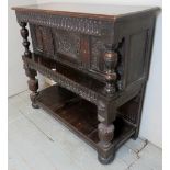 A 17th century oak carved livery cupboard with a central cupboard door beneath a carved frieze and
