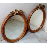 A pretty pair of 20th Century walnut and gilt framed oval wall mirrors with gilt floral carving to