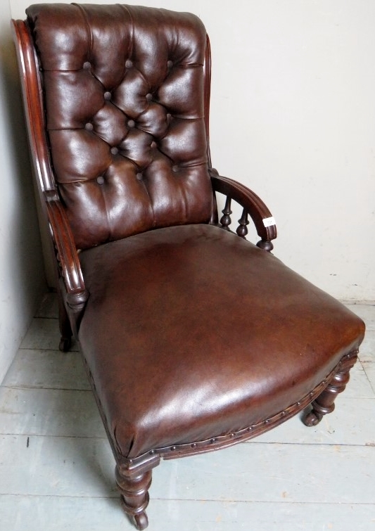 A Victorian mahogany framed armchair upholstered in brown button backed leather,