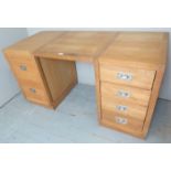 A contemporary light oak pedestal desk with six drawers and campaign style handles.