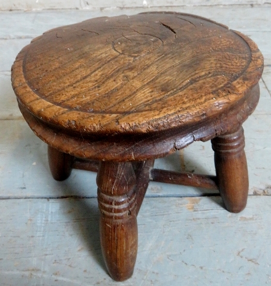 A very small rustic country oak child's milking stool with turned design to legs and cross