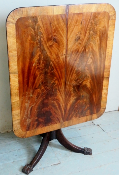 A William IV rectangular tilt top table with a rosewood banded and flame mahogany top over a turned