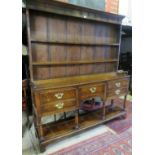 A Georgian country oak dresser with a plate rack top over a central drawer flanked either side by