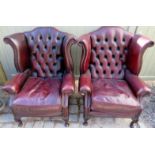 A pair of 20th Century burgundy button backed leather wingback armchairs with decorative brass stud