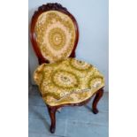 A Victorian mahogany framed nursing chair with floral carving to the top of the oval back rest and