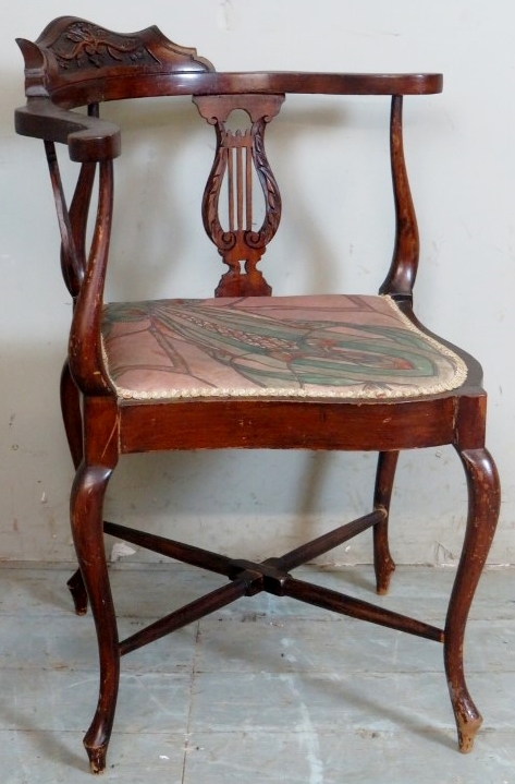 A late 19th Century carved corner chair with harp design arm supports over an upholstered seat.