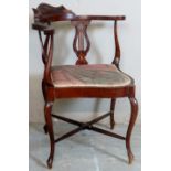 A late 19th Century carved corner chair with harp design arm supports over an upholstered seat.