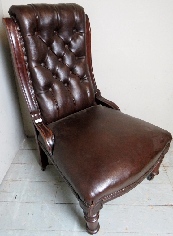 A Victorian mahogany framed library chair upholstered in button backed brown leather and