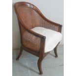 A 19th Century mahogany framed bergere library / desk chair with a loose cream upholstered seat