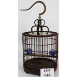 A decorative Chinese bird cage of carved wood and bamboo construction with brass hook and blue and