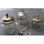 An engraved glass jam pot with silver lid, two other glass jam pots,