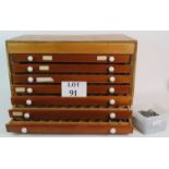 A seven drawer printers type set cabinet with a large quantity of metal printing blocks.