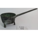 An 18th Century bronze skillet on tripod feet with scroll pattern handle. Overall length: 37cm.