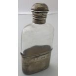 A small glass hip flask with silver cup