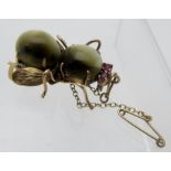 A decorative novelty yellow metal and quartz cat's eye brooch in the form of a bug, with ruby eyes,