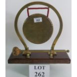 A vintage brass dinner gong on oak stand by 'Nestor' of England. Height: 30cm.